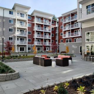 A modern apartment complex with a landscaped courtyard and outdoor seating area.