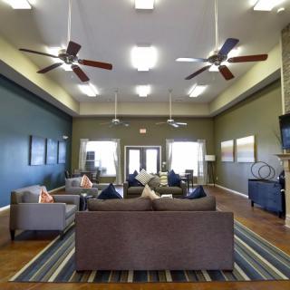 A spacious and modern lounge area with sofas, ceiling fans, and tasteful interior decor.