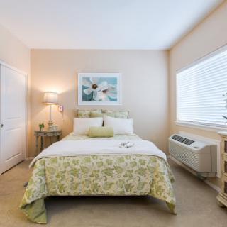 A cozy and well-lit bedroom featuring a double bed with floral bedding, complemented by natural light from the window.
