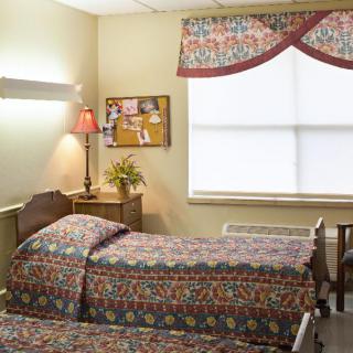 A cozy bedroom with twin beds, a desk, and a bulletin board near the window.