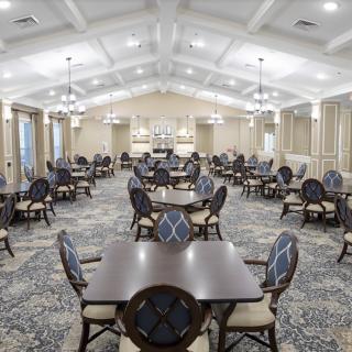 A spacious and elegantly designed dining room with multiple tables and chairs arranged in a symmetrical pattern.