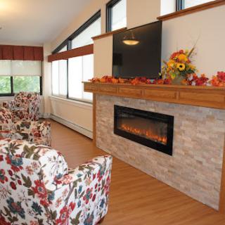 A cozy living room featuring a stylish fireplace, floral-patterned chairs, and autumn decorations.