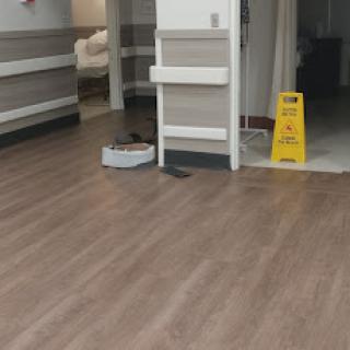A view of a hospital corridor with a caution sign indicating wet floors and a cleaning device.