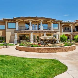A luxurious mansion featuring a grand architectural design with a landscaped garden and central fountain.
