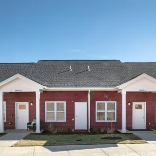 A red duplex with white trim under a clear blue sky.