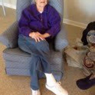 An elderly person sitting comfortably in an armchair indoors.