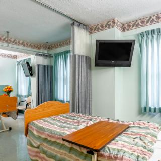A hospital room with a bed, television, and curtains.