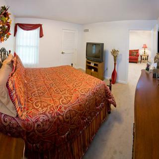 A cozy bedroom with a large bed and a television, featuring warm decor.