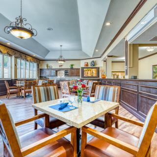 A spacious dining area with neatly arranged tables and chairs, featuring elegant chandeliers and large windows.