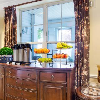 A cozy interior setup featuring a coffee station and fruit display on a wooden buffet table.