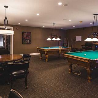 A cozy billiard room featuring two pool tables under stylish lighting.