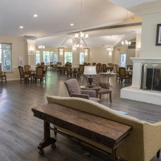 A spacious living and dining area featuring a cozy fireplace, elegant furniture, and a wooden floor.