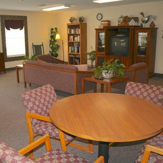 A cozy living room with a sofa, chairs, table, and entertainment center featuring a television and shelves.