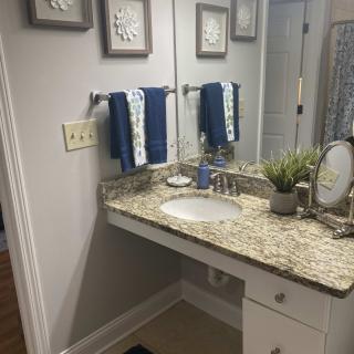 A well-organized bathroom with a granite countertop and blue towels.