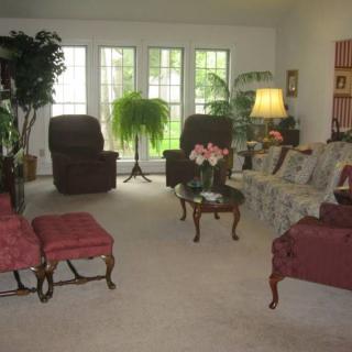 A cozy living room with sofas, chairs, a coffee table, and indoor plants.