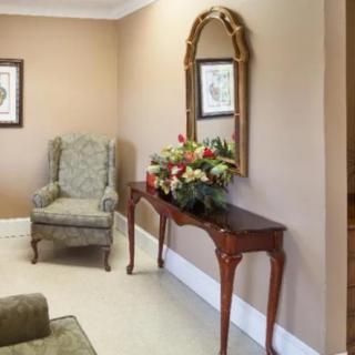 A cozy living area with an armchair, console table, and decorative mirror.