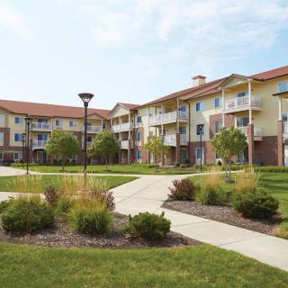 A well-maintained apartment complex with landscaped gardens and a central pathway.