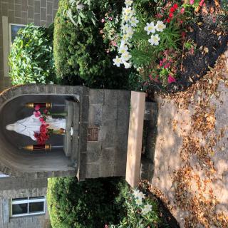 A small garden shrine with a statue surrounded by colorful flowers and greenery.