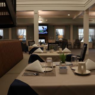 A spacious and elegantly arranged dining area in a restaurant, featuring neatly set tables with napkins and soft lighting.