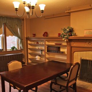 A cozy dining room with a wooden table, chairs, and a fireplace surrounded by bookshelves.