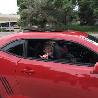 A person inside a red car making a gesture out the window.