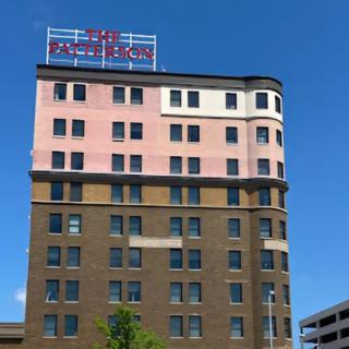 A multi-story building with a hotel sign on top against a clear blue sky.