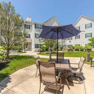Sunny outdoor patio area with furniture and umbrella in an apartment complex.