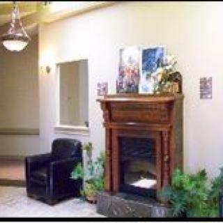 A cozy lobby area featuring a fireplace, armchair, and decorative plants.