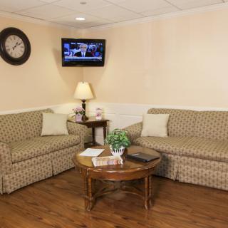 A cozy waiting room with two patterned sofas, a television, and a coffee table.