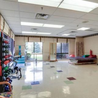 A spacious rehabilitation room equipped with exercise equipment and therapy tools.