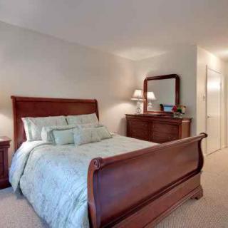 A cozy bedroom featuring a wooden sleigh bed, matching dresser with a mirror, and soft lighting.