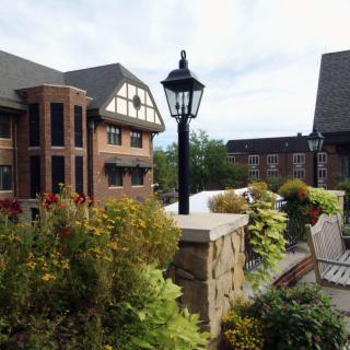 A scenic view of a garden with benches and a traditional-style building in the background.
