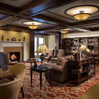 A cozy lounge area featuring comfortable seating, a warm fireplace, and bookshelves filled with books.