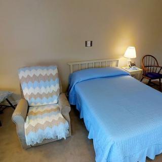 A cozy bedroom setup with a chair, bed, and lamp.