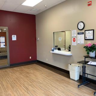 A clean and simple waiting area of a healthcare facility, featuring a reception window and modern decor.