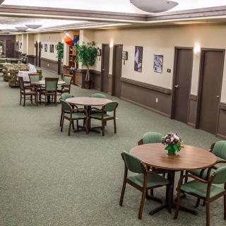 A spacious indoor dining area with multiple tables and chairs, decorated with plants and artwork.