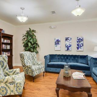 A cozy living room with elegant blue sofas, patterned armchairs, and a wooden coffee table.