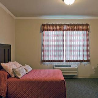 A simple bedroom with a bed, window, and curtains.