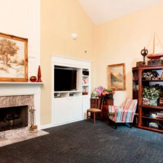 Cozy living room with a fireplace, artwork on the walls, and a well-stocked bookshelf.
