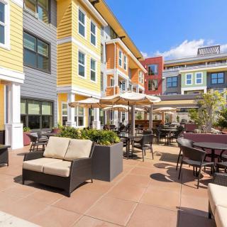A sunny patio area with comfortable seating and umbrellas at a modern apartment complex.