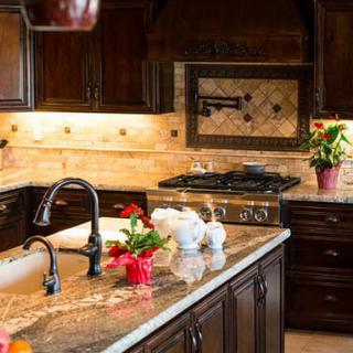 A modern kitchen with dark wood cabinets, a granite countertop, and decorative plants.