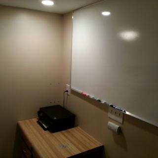 A small office workspace with a whiteboard, printer, and desk.