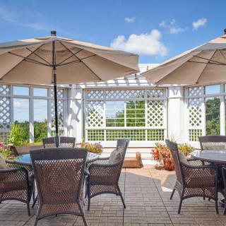 A sunny patio with tables and chairs under large umbrellas.