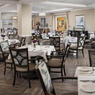 A spacious and elegantly decorated restaurant dining room with neatly arranged tables and chairs.