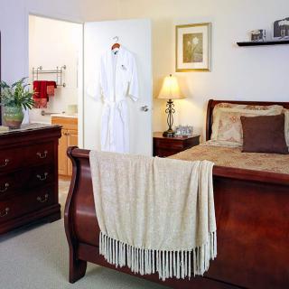 A cozy bedroom with a wooden bed frame, dresser, and ambient lighting.