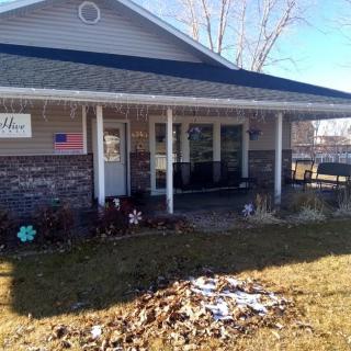 A suburban house with a porch and front yard, featuring patches of snow suggesting a winter setting.