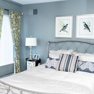 A serene and stylish bedroom featuring soft blue walls, elegant curtains, and charming bird illustrations.