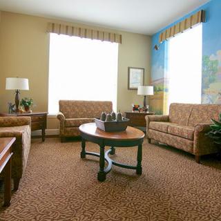 A cozy living room with comfortable sofas and a central coffee table, featuring large windows and warm lighting.