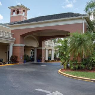 A building entrance with an archway and palm trees lining the driveway.