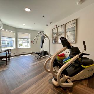 A bright and well-equipped home gym with a stationary bike and exercise machine, featuring modern interior design.